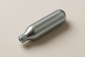 A close-up of a single metallic cream charger on a smooth surface